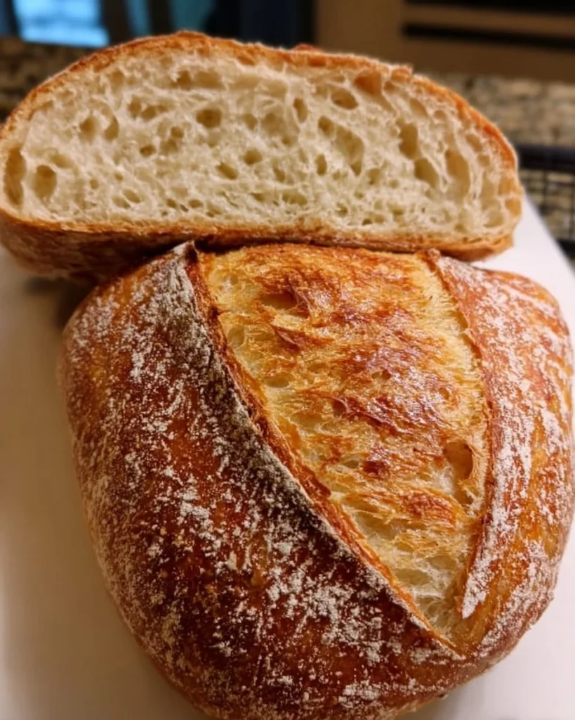 Soft & golden sourdough loaf fresh from the oven, showcasing its crispy crust and airy interior.