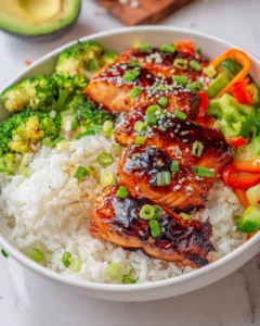Delicious Teriyaki glazed salmon rice bowl with vegetables and chopsticks.
