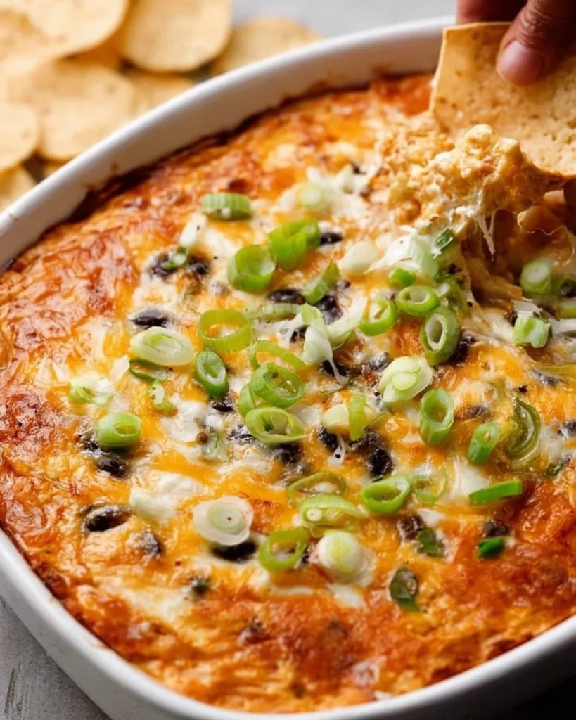 Delicious cheesy bean dip served in a bowl with tortilla chips around it