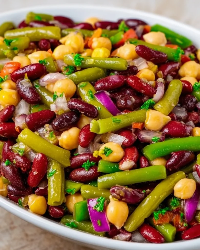 A colorful five bean salad with various beans and fresh vegetables in a bowl.