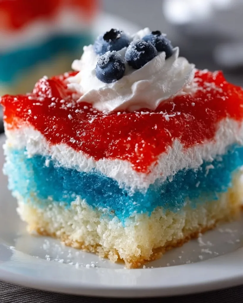 Delicious Red, White, and Blue Poke Cake topped with whipped cream and berries