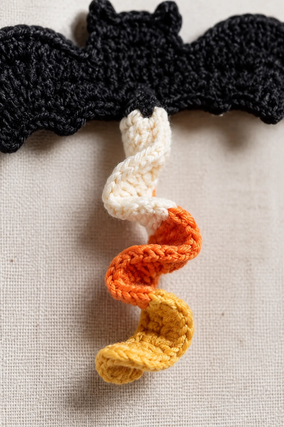 Close view of striped crochet spirals secured beneath a black bat shape.
