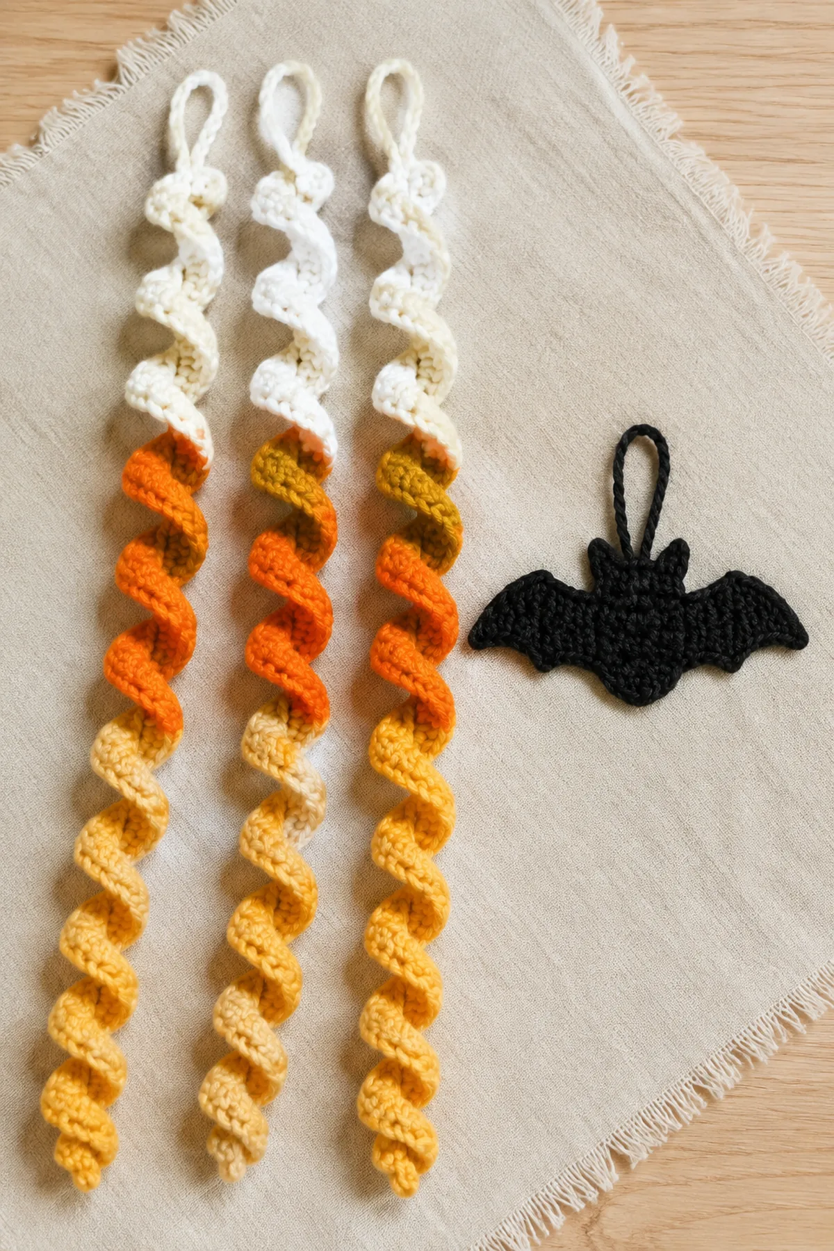 Three completed candy corn spirals beside a flat black crochet bat hanger.