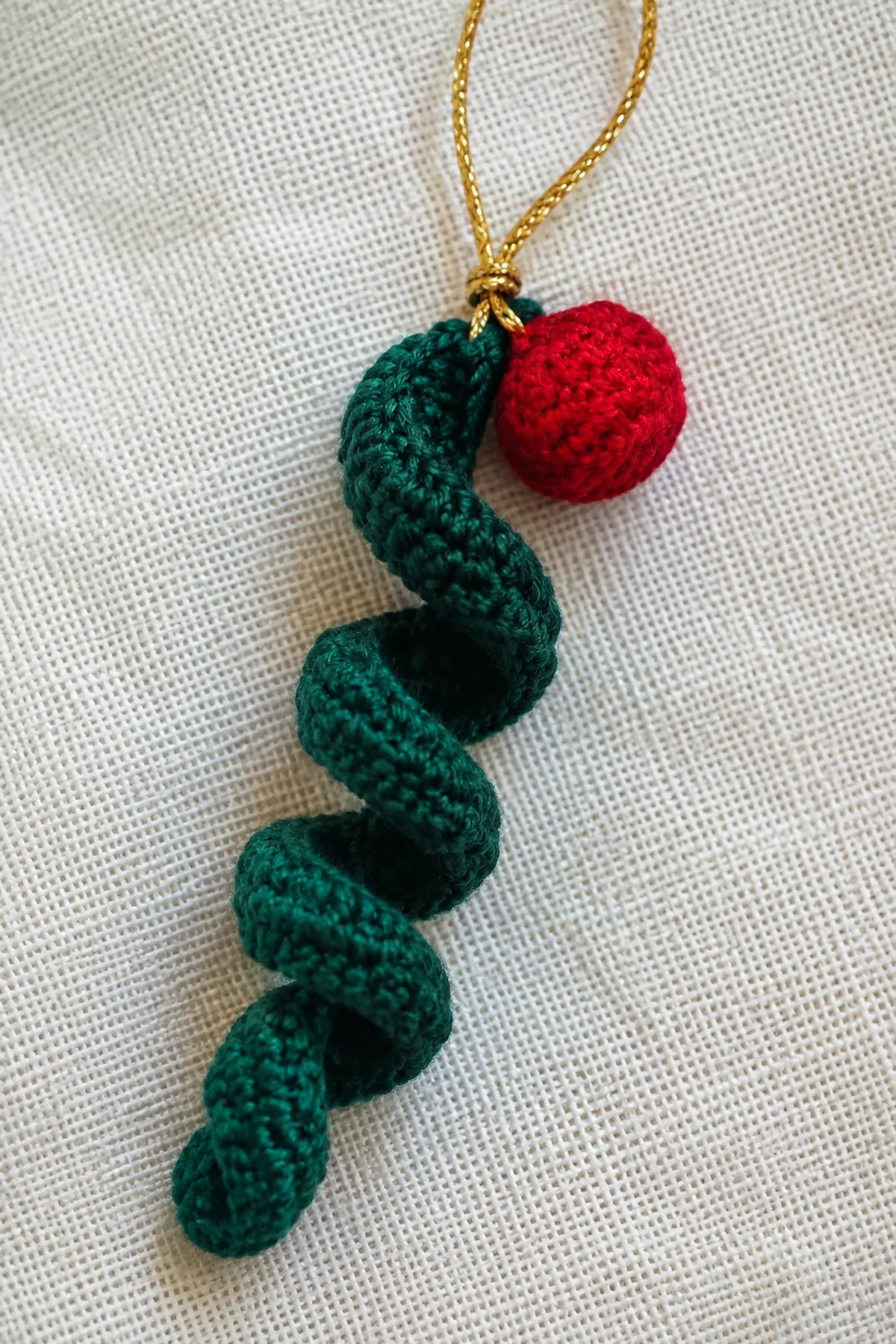 Close view of a red crochet bobble attached to the green Christmas spiral.