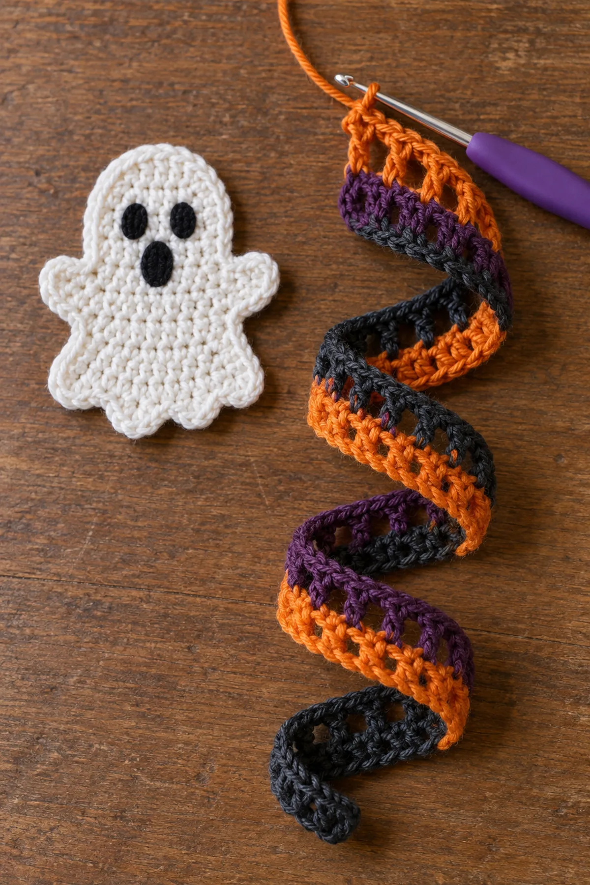 White ghost topper beside an unfinished orange purple and charcoal crochet spiral.