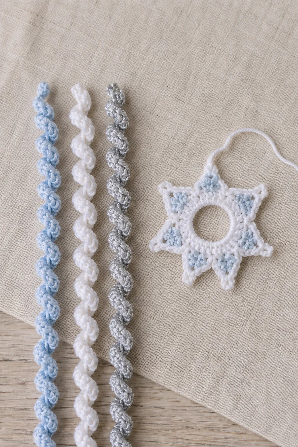 Three winter spirals beside a partially completed crochet snowflake ring.